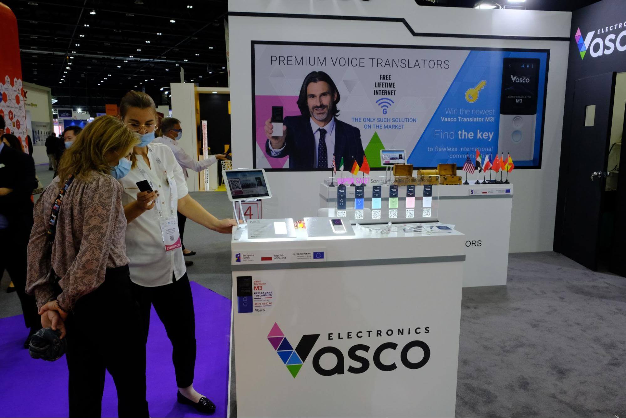 Stoisko Vasco Electronics na GITEX 2021, a na pierwszym planie wystawa translatorów mowy.