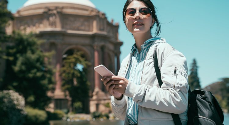 młoda dziewczyna z plecakiem czytająca przewodnik on-line na telefonie komórkowym zwiedzająca Pałac Sztuk Pięknych San Francisco California