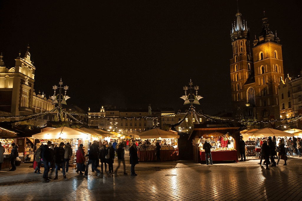 Widok na pięknie oświetlony jarmark na tle krakowskiego rynku.