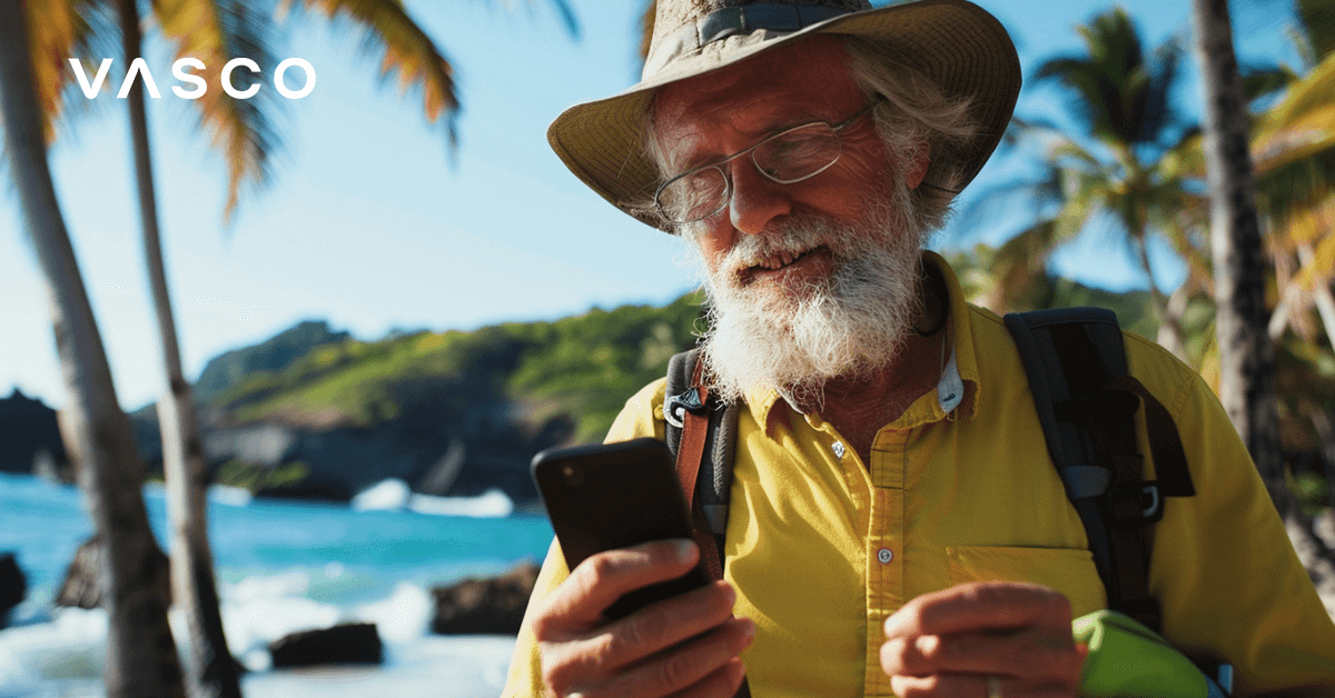 Starszy mężczyzna sprawdzający coś na telefonie na plaży z palmami.