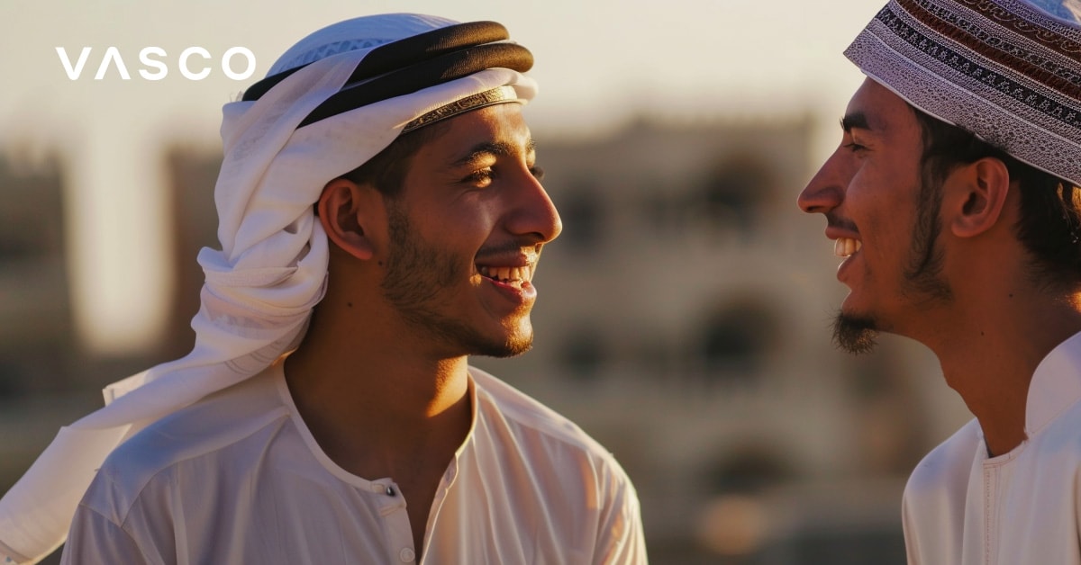 Two men in traditional Arabic attire smiling at each other, demonstrating how to say hello in Arabic.