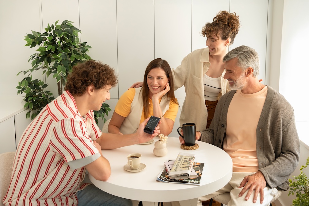 Top 5 par językowych Grupa uśmiechniętych ludzi siedzi przy style i komunikuje się ze sobą przy pomocy Vasco Translatora Q1