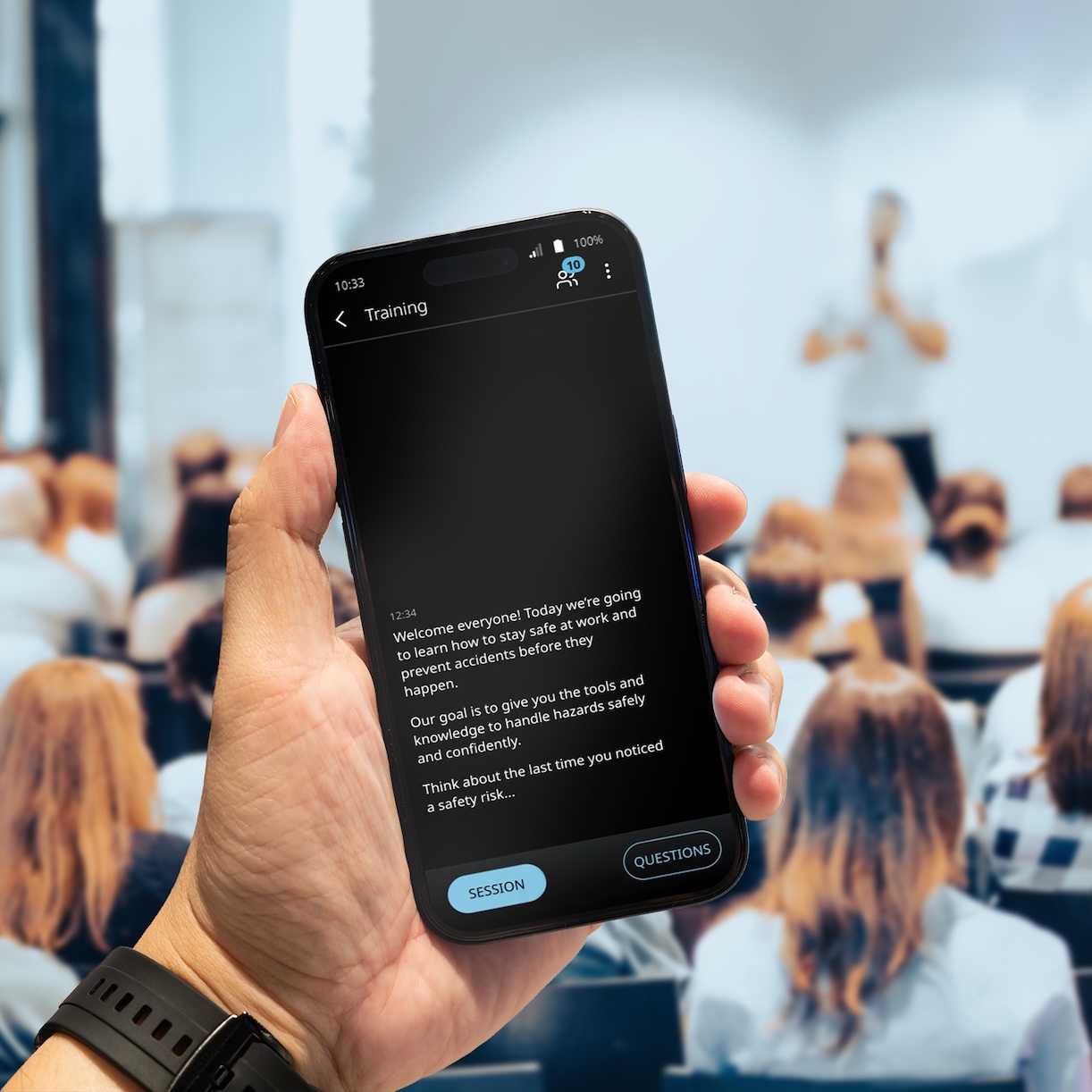 Vasco Audience W sali wypełnionej ludźmi odbywa się prelekcja. Mężczyzna trzyma w dłoni telefon, na którym wyświetlane jest tłumaczenie przy użyciu Vasco Audience