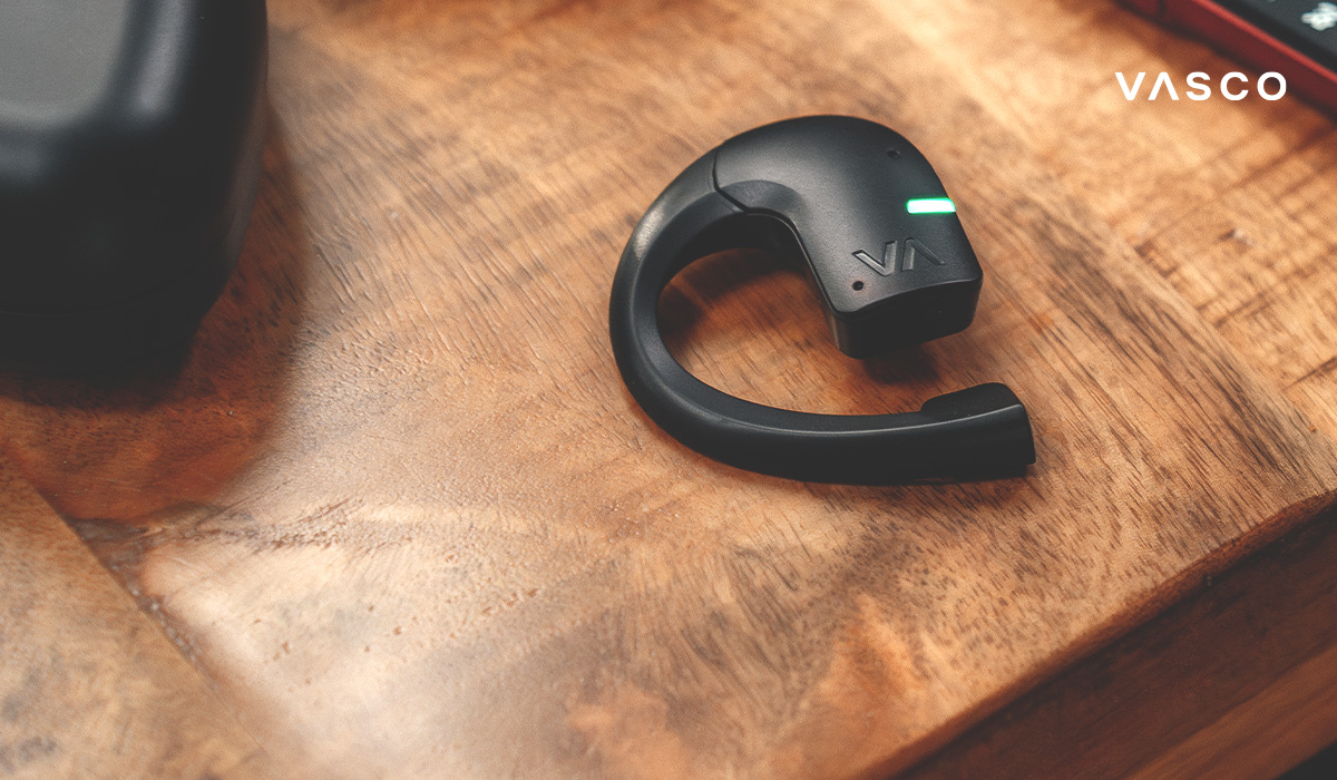 Zbliżenie na słuchawkę Vasco Translator na drewnianym stole z diodą LED