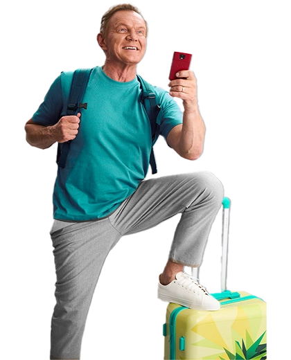 Cezary Pazura stojący za prezentami, w zimowym swetrze, trzyma w rękach pudełko z Vasco Translatorem.