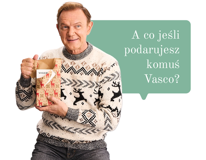 Cezary Pazura w świątecznym swetrze trzyma prezent i otwiera go, a w środku widać pudełko Vasco Translatora. W tle dymek z tekstem: A co jeśli podarujesz komuś Vasco?