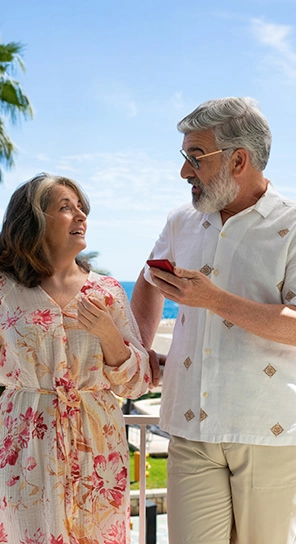 Dwie starsze osoby trzymają urządzenia Vasco Translator V4, rozmawiają ze sobą i prezentują pięć poziomów prędkości odtwarzania.