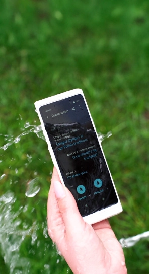 Zbliżenie na Vasco Translator V4 w celu podkreślenia trwałości urządzenia, które zachlapywane jest wodą.