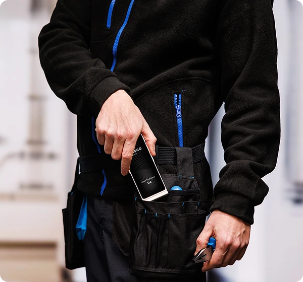 Mężczyzna w stroju roboczym wyjmujący z paska narzędziowego urządzenie Vasco Translator V4.