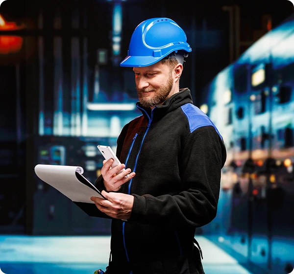 Dwóch mężczyzn rozmawia ze sobą; kierowca ciężarówki trzyma Vasco Translator V4, a osoba stojąca naprzeciwko, prawdopodobnie pracownik magazynu, trzyma dokumenty. Komunikują się za pomocą Vasco Translatora.