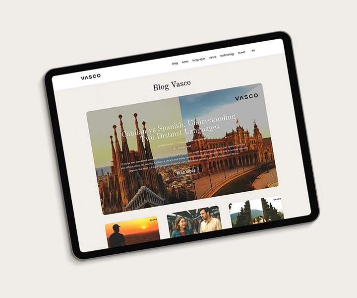 Tablet wyświetlający stronę Vasco Blog, na której widnieje główny artykuł zatytułowany „Kataloński a hiszpański: zrozumienie dwóch odrębnych języków” wraz ze zdjęciami zabytków Barcelony, takich jak Sagrada Familia i Plaza de España, oraz mniejszymi miniaturami innych wpisów poniżej.