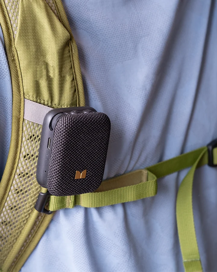 Czarny mini głośnik Bluetooth przypięty do oliwkowo-zielonego paska plecaka