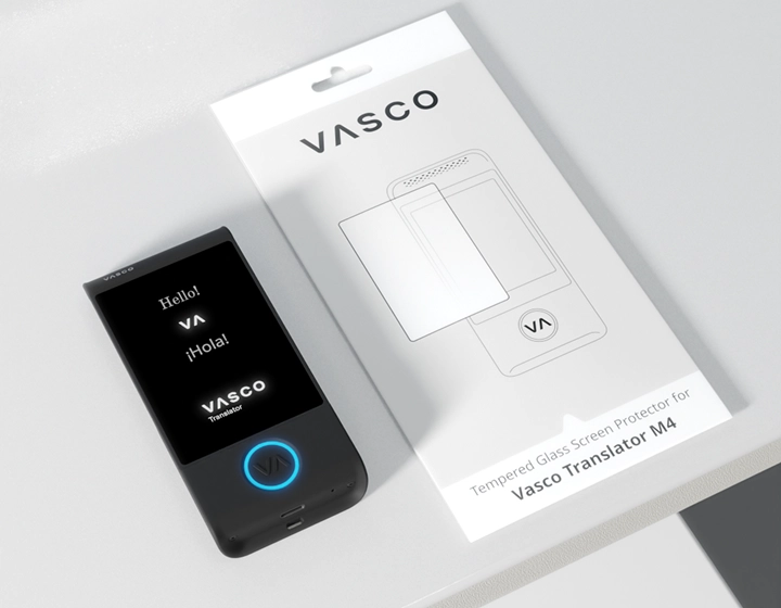 Tłumacz Vasco M4 z niebieską diodą LED oraz z logo Vasco, leży na stole obok opakowania dla szkła ochronnego do tłumacza Vasco M4.